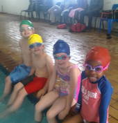 4 students sitting on the edge of the pool waiting for the sign to enter